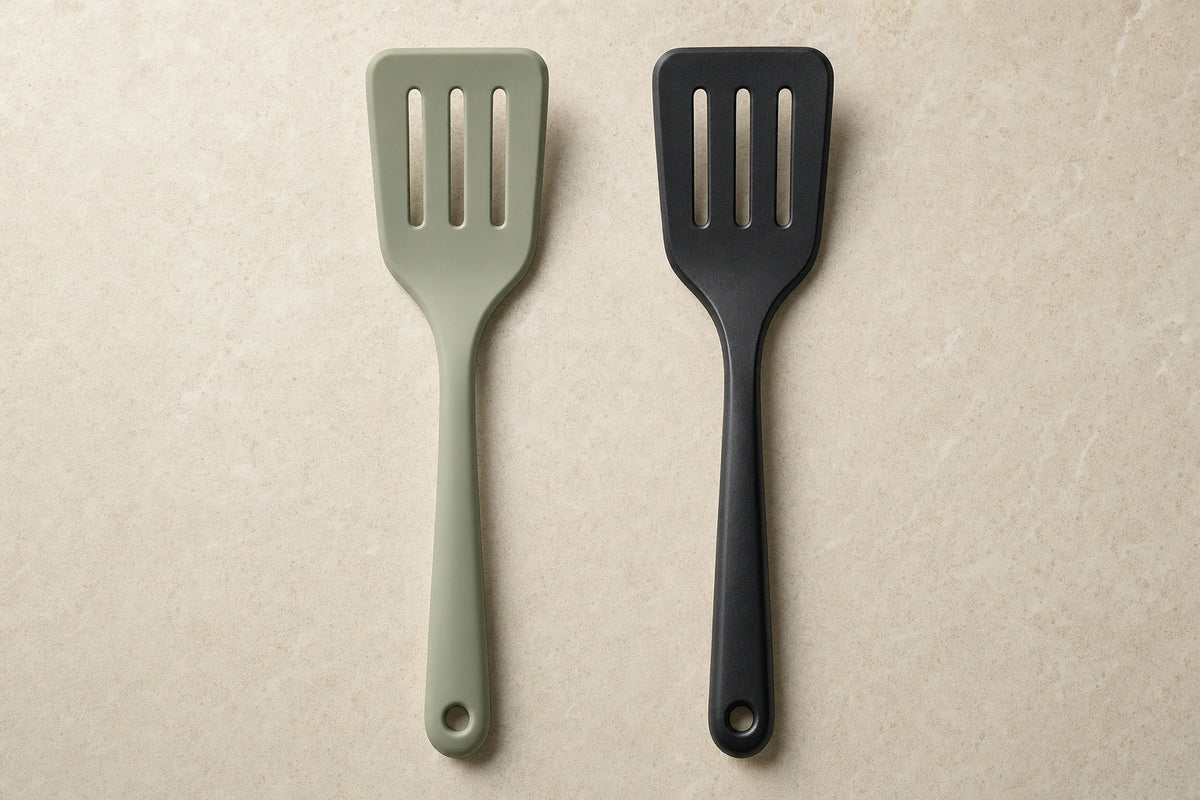 Illustrative side-by-side comparison of a muted sage silicone slotted turner and a black plastic slotted turner on a pale stone surface.